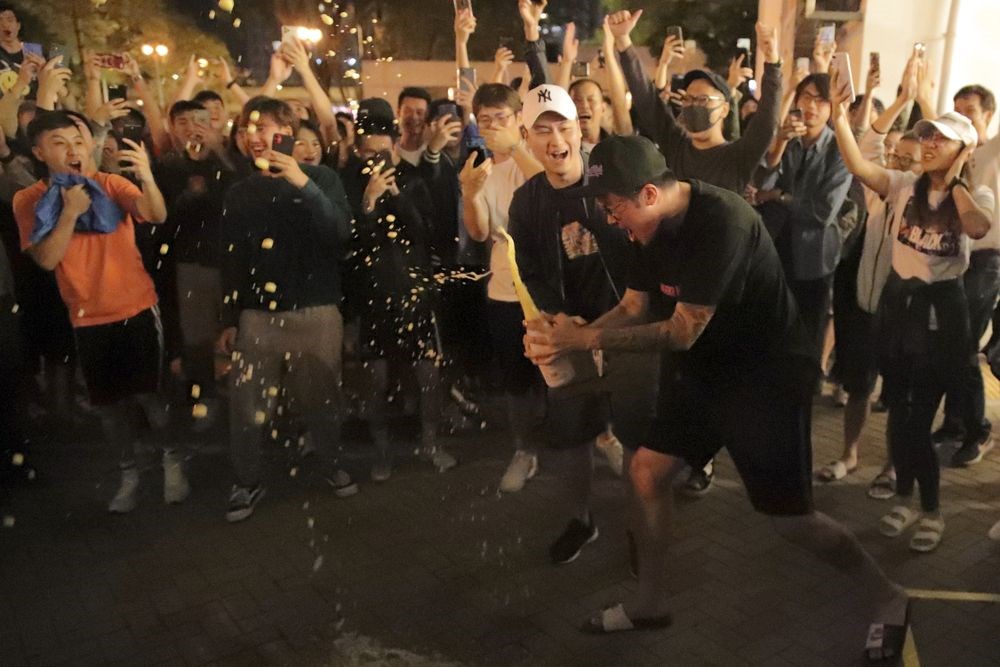 香港泛民主派在地方區議會選舉中大獲全勝，親中建制派則大敗。圖為建制派候選人何君堯確定落選後，泛民派支持者在街頭開香檳慶祝。（美聯社）
